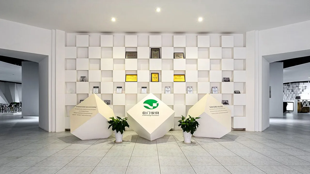 Vestíbulo de la sala de exposición de Chairmeng en Anji — pared de marca 乾门家具 con placas de honor, sala de taburetes a la izquierda y showroom de producto a la derecha